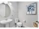 Cozy powder room with a pedestal sink, round mirror, and neutral color palette at 13800 Chauvin Ave, Orlando, FL 32827