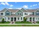 Charming exterior view of townhomes featuring a manicured lawn, and a covered porch with classic white pillars at 13809 Luna Harvest Ave, Winter Garden, FL 34787