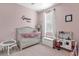 Bedroom featuring pink walls, a crib, a play kitchen, and natural light from the window at 1452 Hopedale Pl, Sanford, FL 32771