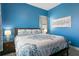 Cozy bedroom featuring blue walls, a comfortable queen bed, and soft, inviting lighting at 1543 Corolla Ct, Reunion, FL 34747