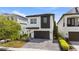 Modern two-story home with a dark garage door, white and dark grey exterior, and a well-maintained front yard at 1543 Corolla Ct, Reunion, FL 34747
