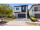 Modern two-story home showcasing a dark garage door, white and dark grey exterior, and manicured landscaping at 1543 Corolla Ct, Reunion, FL 34747