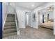 Light-filled foyer with modern staircase, light wood floors, and view into adjacent bedroom space at 1543 Corolla Ct, Reunion, FL 34747