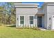 Landscaped front of house with modern gray stucco, black door and brick paver walkway at 17135 Sw 41 Ct, Ocala, FL 34473