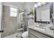 Updated bathroom featuring a tiled shower, floating shelves, and granite vanity with stainless steel faucet at 1817 Snaresbrook Way, Orlando, FL 32837