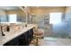 Bathroom with black cabinets, marble countertops, and walk in shower with pebbled floor at 1855 Partin Terrace Rd, Kissimmee, FL 34744