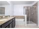 Bathroom with double sinks, granite countertop, bathtub and glass door shower stall at 188 Whispering Pines Way, Davenport, FL 33837