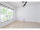 Bright bedroom with neutral tile floors, ceiling fan, and large window offering natural light at 188 Whispering Pines Way, Davenport, FL 33837