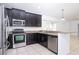 Eat-in kitchen features stainless steel appliances, dark cabinetry, and granite countertops at 188 Whispering Pines Way, Davenport, FL 33837