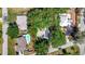 Aerial view of a property with lush trees, solar panels, pool, and well-maintained landscaping, surrounded by neighborhood homes at 24 Cypress Ave, St Cloud, FL 34769