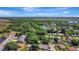 Aerial view of a tree-covered property in a residential neighborhood, with a pond and open fields visible in the distance at 24 Cypress Ave, St Cloud, FL 34769