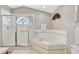 Bright bathroom featuring a glass-enclosed shower, soaking tub, and tiled walls at 24 Cypress Ave, St Cloud, FL 34769