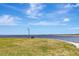 Scenic waterfront view featuring a grassy area with bench and light post under a blue, partly cloudy sky at 24 Cypress Ave, St Cloud, FL 34769