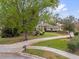Landscaped front yard with a winding driveway leading to a charming home, enhanced by mature trees at 2991 Timpana Pt, Longwood, FL 32779