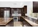 Modern kitchen featuring dark cabinets, granite countertops, stainless steel appliances, and a functional design at 2991 Timpana Pt, Longwood, FL 32779