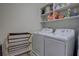 Laundry room with white washer and dryer and open shelving with cleaning supplies at 3345 Messina Dr, Lake Mary, FL 32746