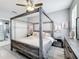 Bedroom with a canopy bed, wood floors, muted walls, and view into the bathroom with cabinets and shower at 4103 Calabria Ave, Davenport, FL 33897