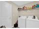 Practical laundry room equipped with a washer, dryer, and storage shelving for convenience at 429 N Andrea Cir, Haines City, FL 33844