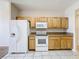 A bright kitchen with light wood cabinetry, a white electric range, and a matching white refrigerator at 4919 Culdesac Ct, St Cloud, FL 34772