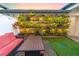 Inviting back patio showcasing a unique vertical garden with lighting, cozy seating, and artificial turf at 5156 Caspian St, St Cloud, FL 34771