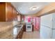 Kitchen featuring wooden cabinets, granite countertops, white appliances, and tiled flooring, combining classic charm with convenience at 5424 Blue Grass St, Orlando, FL 32810