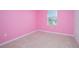 Bright pink bedroom with natural light, featuring neutral carpeting and base trim at 5709 Sagunto Dr, Davenport, FL 33897