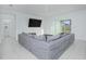 Modern living room with a large gray sectional, a wall-mounted TV, and sliding glass doors to the backyard at 5709 Sagunto Dr, Davenport, FL 33897