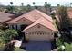 Aerial view of a home with a tile roof, beautiful landscaping, and a paved driveway at 603 Russ Pond Dr, Kissimmee, FL 34759