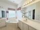 Well-lit bathroom with dual vanities, large tub, and large mirror at 603 Russ Pond Dr, Kissimmee, FL 34759