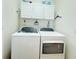Bright laundry area equipped with a modern washer and dryer set and storage cabinets above at 603 Russ Pond Dr, Kissimmee, FL 34759
