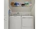 Bright laundry area featuring a stacked washer and dryer, plus storage shelving for supplies at 6067 Blue Lily Way, Winter Garden, FL 34787