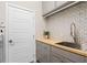 Well-organized laundry room with gray cabinets, wood countertop, and patterned backsplash at 637 Conservation Blvd, Groveland, FL 34736
