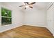This bedroom has hardwood floors, a ceiling fan, and a large window for plenty of light at 703 Sailfish Rd, Winter Springs, FL 32708