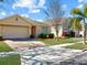 Well-maintained single-story home with a brick driveway and manicured landscaping on a sunny day at 734 Andalusia Loop, Davenport, FL 33837