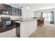 Well-equipped kitchen with dark cabinetry, granite countertops, and an adjacent dining area at 734 Andalusia Loop, Davenport, FL 33837