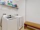 Bright laundry room with modern washer, dryer, shelf and a small bench at 734 Andalusia Loop, Davenport, FL 33837