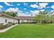 Rear exterior featuring a well maintained lawn, the back of the house, and mature landscaping at 8244 Oakland Pl, Orlando, FL 32819