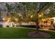 Expansive backyard with a lush lawn, mature tree with lights, and a charming covered patio at 8244 Oakland Pl, Orlando, FL 32819