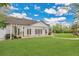 Back of the house with a brick patio, pergola, french doors, a large lawn, and mature trees at 8244 Oakland Pl, Orlando, FL 32819