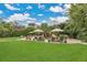 Landscaped backyard featuring manicured lawn, pool with rock features, tiki umbrellas, and privacy landscaping at 8244 Oakland Pl, Orlando, FL 32819