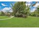 Large backyard surrounded by mature trees, foliage, and shrubbery with a glimpse of the pool at 8244 Oakland Pl, Orlando, FL 32819