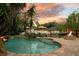 Stunning backyard oasis featuring a freeform pool, lounge area, and cozy fire pit against a vibrant sunset backdrop at 8244 Oakland Pl, Orlando, FL 32819