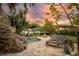 Inviting backyard featuring a freeform pool, patio seating, firepit, and a tranquil rock feature amidst lush landscaping at 8244 Oakland Pl, Orlando, FL 32819