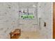 Walk-in shower featuring a neutral tile surround, bench, rainfall shower head and large window at 8244 Oakland Pl, Orlando, FL 32819