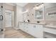Elegant bathroom featuring double sinks, framed mirrors, white cabinetry, wood-look flooring and granite counters at 8336 Boyla Ct, Windermere, FL 34786