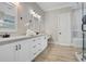 Elegant bathroom featuring double sinks, framed mirrors, white cabinetry, wood-look flooring and granite counters at 8336 Boyla Ct, Windermere, FL 34786