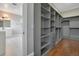 Walk-in closet featuring custom shelving and drawers with hardwood floors and access to ensuite bath at 8336 Boyla Ct, Windermere, FL 34786