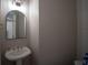 Powder room with pedestal sink and arched mirror, offering a convenient and stylish space at 9833 Camberley Cir, Orlando, FL 32836