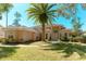 Inviting Mediterranean home with a tile roof, stucco facade, and mature landscaping including a beautiful palm tree at 9833 Camberley Cir, Orlando, FL 32836