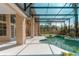 View of the screened-in pool, showing the pool's unique shape, surrounding landscaping, and the home's architectural details at 9833 Camberley Cir, Orlando, FL 32836
